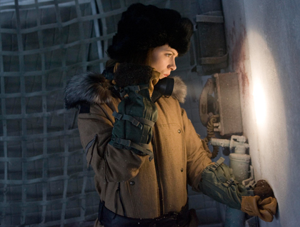Kate Beckinsale holding a flashlight and investigating .